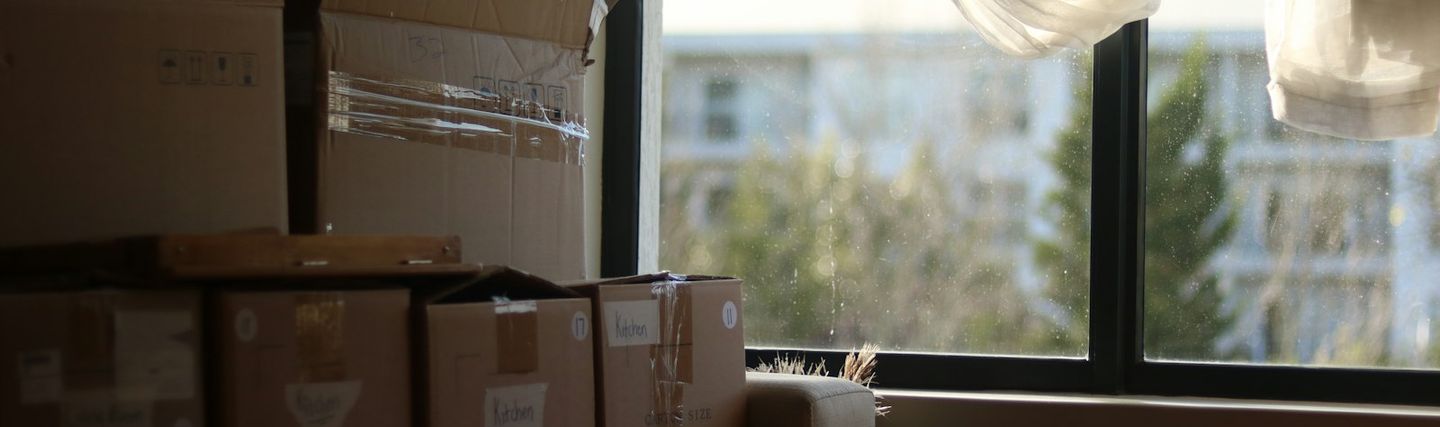 Moving boxes stacked in a bright room in front of a window
