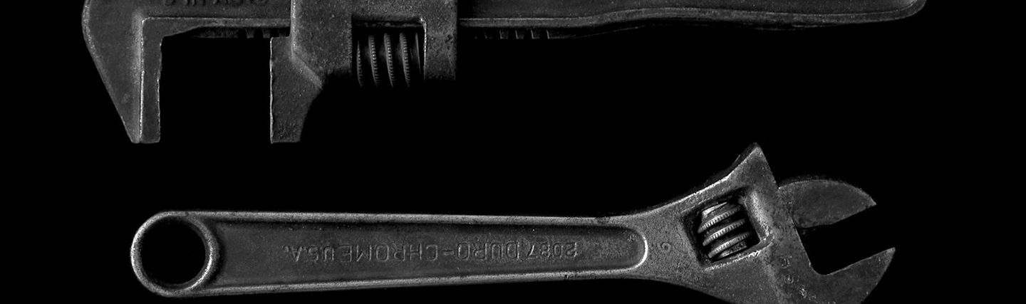 An adjustable wrench and a pipe wrench on a dark background
